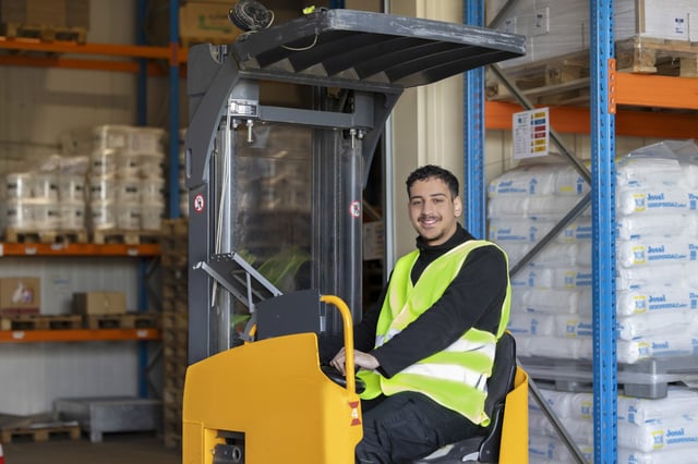 Person mit Warnweste auf Gabelstapler