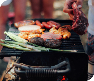 Grill belegt mit Würstchen, Fleisch und grünem Spargel